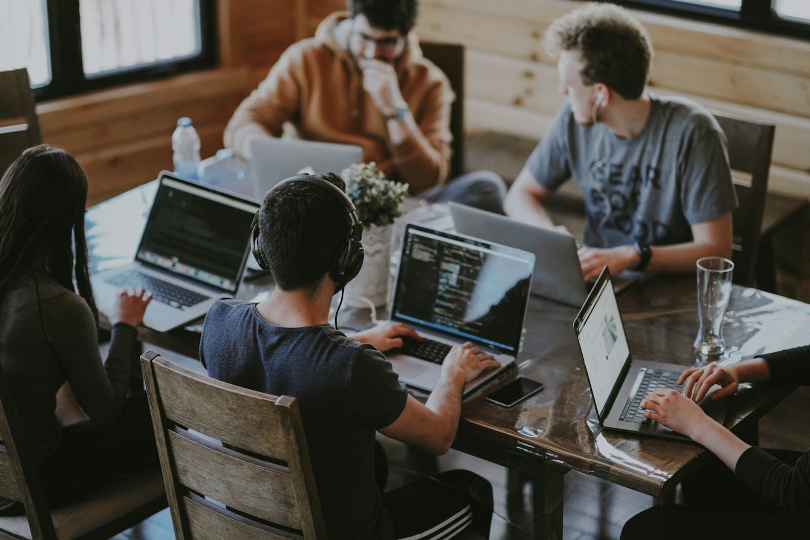 A team working together at one long desk, each on their own screen.