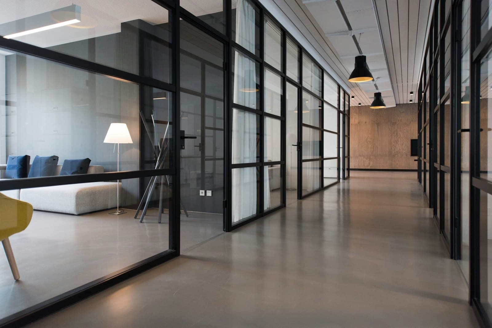 An empty office corridor lined with glass meeting rooms.